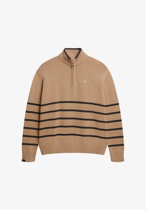 Suéter de punto beige con cuello acanalado, cremallera y franjas horizontales negras en el cuerpo. Presenta un pequeño logo en el pecho.