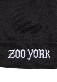 Fekete kötött sapka, fehér hímzett "ZOO YORK" felirattal, merész betűtípussal. Az anyag textúrált és rugalmas, a melegség érdekében tervezve.