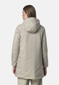 Parka isolante di un beige chiaro con cappuccio, caratterizzata da una texture liscia e un design di lunghezza media. Maniche lunghe e una forma semplice e affusolata.
