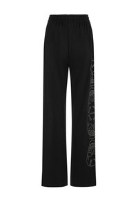 Zwarte wijde broek gemaakt van zachte stof met een elastische tailleband. Heeft een gedetailleerd wit schedelpatter aan de linkerkant.