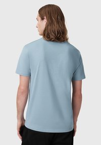 Maglietta in cotone azzurro chiaro con maniche corte, scollatura a girocollo e vestibilità rilassata, mostrata dal retro con una texture liscia.