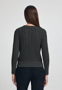 Pull en maille câble gris avec encolure ronde et ourlet côtelé, doté de manches longues et d'un motif texturé au dos.
