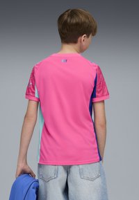 T-shirt med kort ärm, rosa kropp, blå och aqua detaljer, texturerade ärmar och "CITY" tryckt på baksidan i blått. Avslappnad passform.