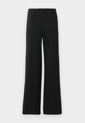 Pantalons larges noirs avec des rayures blanches verticales. Fabriqués dans un tissu texturé, présentant une taille haute et une coupe ample.