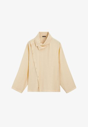 Haut beige à manches longues avec fermeture asymétrique à boutons et large col, fabriqué en tissu texturé.