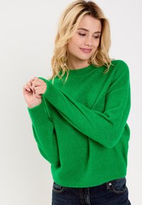 Groen gebreide trui met een ronde hals, geribbelde manchetten en zoom. Gemaakt van zacht materiaal, met een relaxte pasvorm en een minimale textuur.