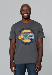 Graues Baumwoll-T-Shirt mit einem bunten Wohnmobil-Graphic, das mit Surfboards versehen ist, umgeben von dem Text "REISE UND SURFE DIE WELT".