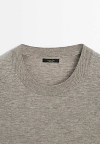 Harmaa neulepusero pyöreällä kaula-aukolla, jossa on ribbireunukset kauluksessa ja pehmeä, eläväinen kangas. Tässä on merkki "Massimo Dutti."