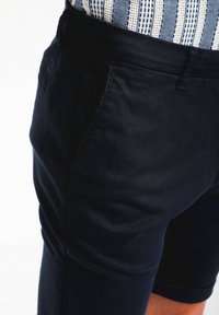 Pantalones cortos de color azul marino con un ajuste slim, hechos de tela suave. Cuenta con bolsillos cosidos y dobladillo limpio, adecuados para un uso casual.
