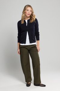 Marineblauwe cardigan met lange mouwen, knoopsluiting aan de voorkant en geribbelde accenten, gecombineerd met olijfgroene wijde broek en zwarte geperforeerde platte schoenen.