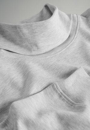 Grå turtleneck-top i bomuldsblanding med ribbede detaljer ved kraven og manchetterne, der har en glat tekstur og et afslappet design. Nærbillede af stoffet.