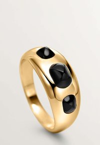 Anillo de oro con un diseño liso y redondeado que presenta tres piedras ovaladas negras incrustadas. La superficie es reflectante y pulida.