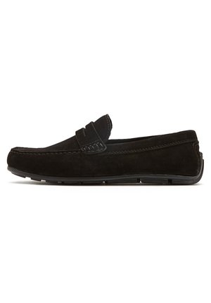 Mocasines de ante negro con suela de goma plana, que presentan un diseño cosido y una cinta decorativa en la parte delantera.