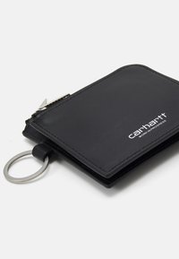 Portefeuille en cuir noir avec une texture lisse et des bords cousus. Comprend un porte-clés en métal attaché et un logo de marque sur le devant.