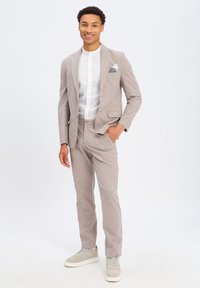 Lichtgrijs linnen suit met een slim fit, voorzien van notch revers, een twee-knoopsluiting, en een wit overhemd. Geaccentueerd met een gebloemd pochet en casual grijze sneakers.