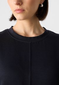 Marineblauwe sweatshirt met een ronde halslijn, een zachte textuur en een naaddetail dat verticaal over de voorkant loopt.