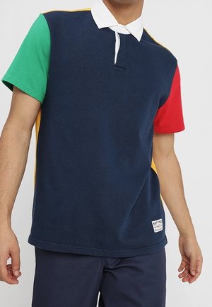 Poloshirt mit kurzen Ärmeln, navyfarbenem Körper, grünen, roten und gelben Akzenten, weißem Kragen, strukturiertem Stoff und einem kleinen Logopatch am Saum.