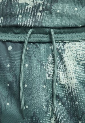 Pantaloni jogger verdi con motivo, caratterizzati da un tessuto testurizzato, vita elastica e dettagli con cordino, con una combinazione di tonalità scure e chiare.