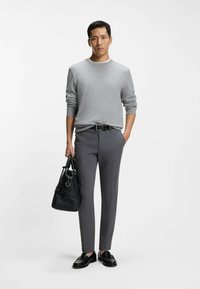 Gray crew-neck sweater, gray tailored pants, black leather loafers, and a black textured handbag with shoulder straps.