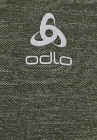 Green athletic top made of textured fabric featuring a subtle pattern, with a prominent white "Odlo" logo and abstract design elements.