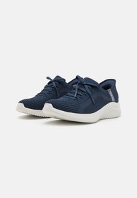 Marineblaue Sportschuhe mit einer strukturierten Oberfläche, abgerundeter weißer Sohle und Schnürsenkeln. Verfügt über ein dezentes Muster und eine gepolsterte Rückseite für Unterstützung.