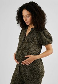 Tehotenský outfit z olivovo zelenej tkaniny s leopardím vzorom, s výstrihom do V a nariasenými rukávmi, navrhnutý pre pohodlné nosenie.