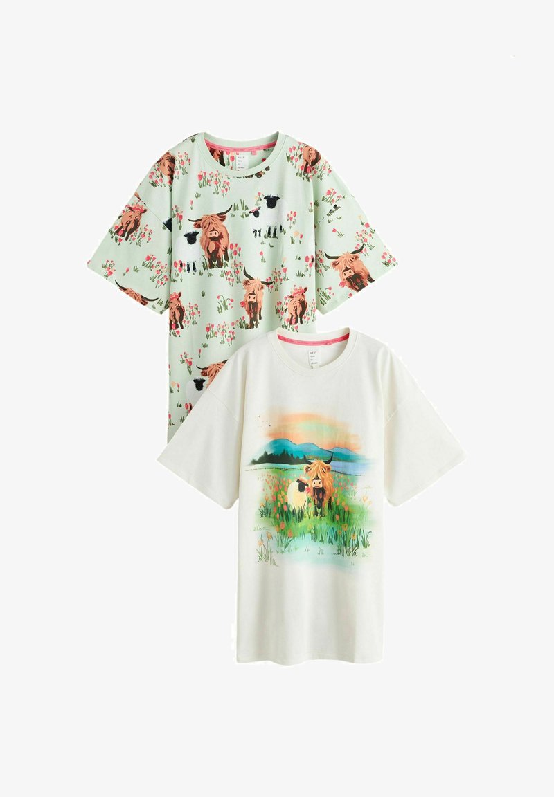 To kortærmede skjorter: en mintgrøn med gentaget ko- og fårmønster, en hvid med ko og får på en blomstereng med bjergbaggrund.