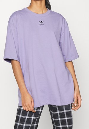 Fioletowy, oversize'owy t-shirt wykonany z bawełny, z okrągłym dekoltem i krótkimi rękawami, z czarnym logo Adidas na piersi.