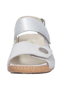 Light gray sandal with a textured silver strap, adjustable closure, and a round metallic accent. Cork sole with stitching detail. Open-toe design.