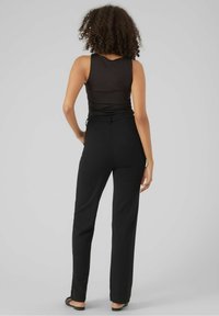 Czarne spodnie o prostych nogawkach wykonane z gładkiej tkaniny z elastycznym pasem. Połączone z dopasowanym czarnym topem na ramiączkach. Minimalistyczny design.