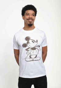 Hvid bomulds t-shirt med en skitseret illustration af en tegneserievæg. Designet inkluderer sorte konturer og detaljer, med runde ører og en butterfly.