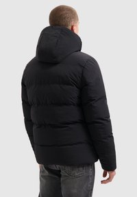 Zwart gewatteerd jasje met capuchon, voorzien van doorgestikte secties, een gladde textuur en een slim fit. De achteraanzicht benadrukt het materiaal en ontwerpelementen.