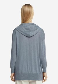 Ljusblå, långärmad huvtröja med avspänd passform. Mjuk textur, ribbade ärmslut och nederkant, med en framåtvänd huva.
