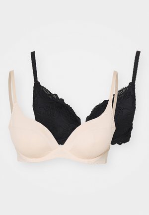 Zwei Büstenhalter: einer in Nude mit glattem Stoff und Schaumstoff-Cups, der andere in Schwarz aus Spitze mit gewellten Akzenten und verstellbaren Trägern.
