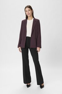 Blazer viola scuro su una maglia bianca, abbinato a pantaloni neri a vita alta. Presenta maniche lunghe e tacchi a punta neri. Tessuto liscio.
