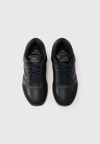 Svarte sneakers med teksturert skinnfinish, med lavt design, rund tå og sentral snøring. Logoer synlige på innersålene.