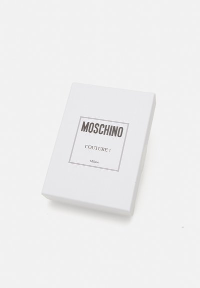 Hvit rektangulær emballasje med en flat overflate. Svart "MOSCHINO COUTURE!"-etikett i et rektangel foran. Enkelt design med matte teksturer.
