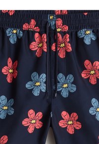 Pantaloni da bagno navy con vivaci motivi floreali rossi e blu. Vita elastica con cordoncino per la regolazione. Tessuto morbido e leggero.