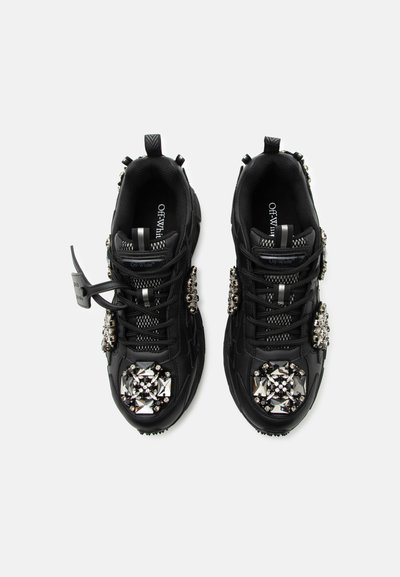 Μαύρα sneakers Off-White με χοντρές σόλες, μαύρα κορδόνια και μεγάλες ασημένιες κρυσταλλικές διακοσμήσεις στα δάχτυλα και στα πλάγια, σε θέαση από πάνω.