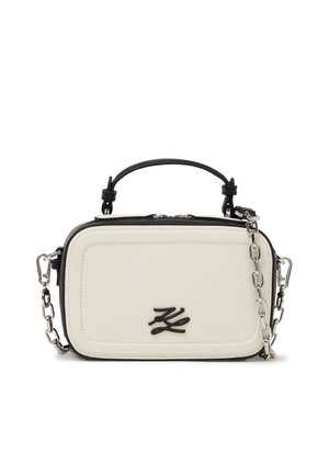 Small rectangular cream handbag with black trim, top handle, and silver chain strap, featuring a black logo on the front.