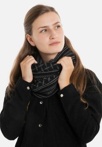 Gehaakte zwarte en grijze sjaal in een oneindige stijl met een subtiel geometrisch patroon, los om de nek gedragen, van een textuurstof.