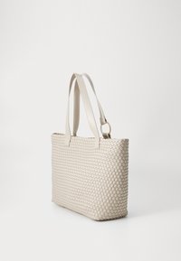 Sac tissé beige de forme plate, avec deux anses plates et une surface texturée. Il présente un motif diagonal subtil et un accent en métal doré.