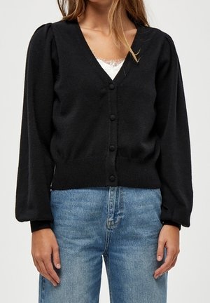 Cardigan nero con scollatura a V, maniche puff lunghe e chiusura con bottoni, realizzato in materiale morbido. Abbinato a jeans di denim azzurri.