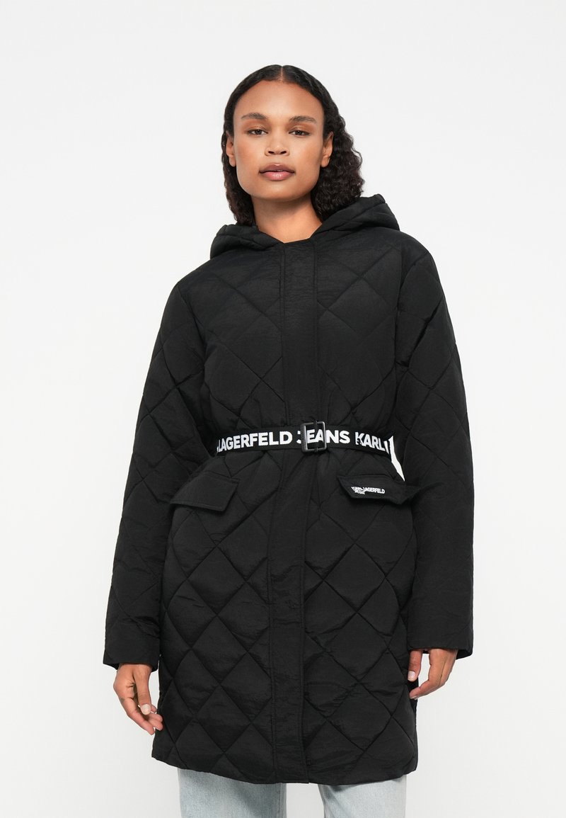 Cappotto nero trapuntato con cappuccio, dotato di vita con cinturino e accenti del logo. Due tasche frontali e texture a motivo diamante. Vestibilità casual.