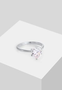 Silberring mit einem herzförmigen, klaren Edelstein, im Krappenfassungsstil, mit glattem Band und graviertem Innenmuster. Einfaches, klassisches Design.
