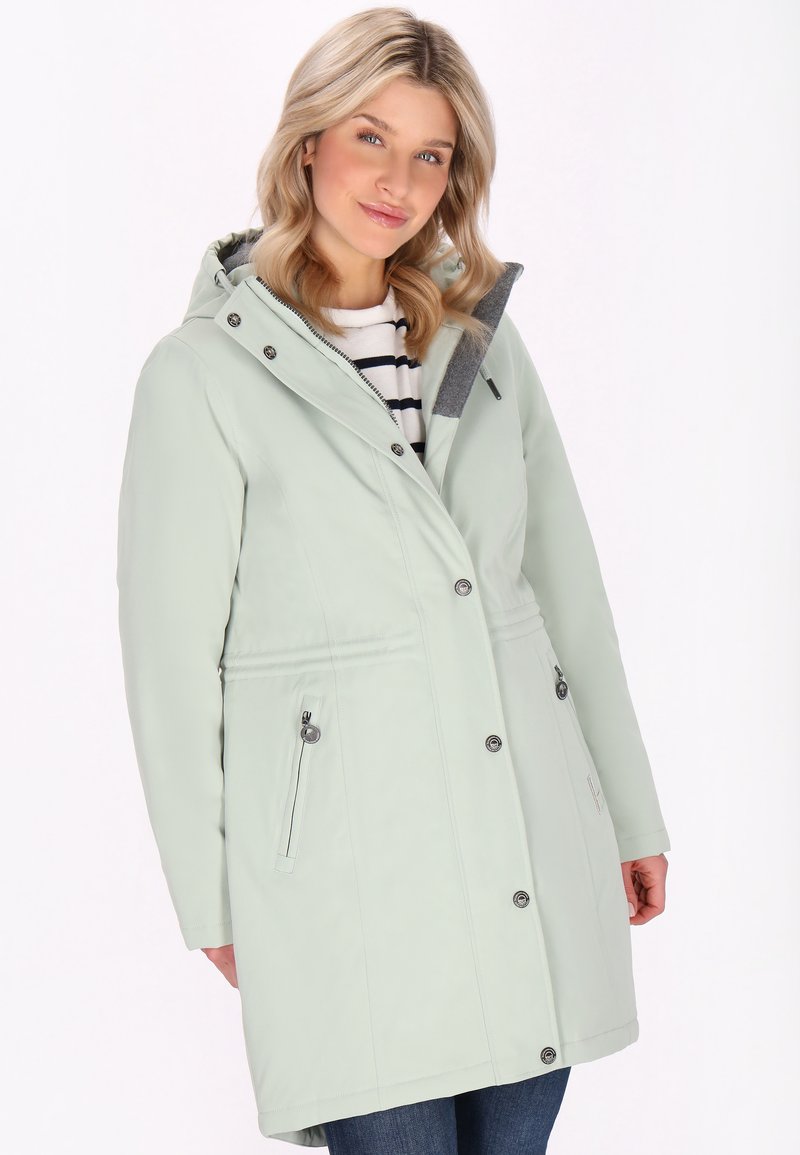 Cappotto impermeabile verde menta con cappuccio, bottoni a pressione, tasche con zip frontali e accenti grigi vicino al colletto. Tessuto morbido, design fino al ginocchio.