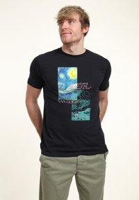 Camiseta de algodón negra con estampados de obras de Van Gogh, incluyendo "La Noche Estrellada", con acentos en rosa y verde. Manga corta, escote redondo.