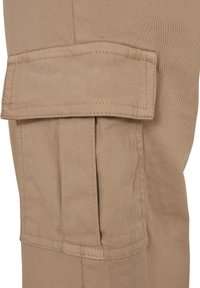 Pantalon cargo beige avec une poche à rabat, fabriqué en tissu mélange de coton, avec des détails cousus et une finition douce et texturée.