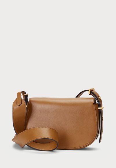 Karamelli naha ristkoti, millel on kaardus kuju, sile viimistlus ja eemaldatav õlapael. Kuldne riistvara aktsent.