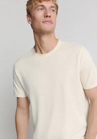 Crème-kleurig t-shirt met korte mouwen, een ronde hals en een ribbelstructuur, slim fit en zonder zichtbare logo's of patronen.